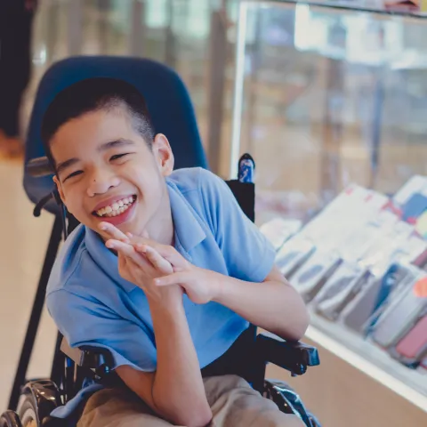 Disabled child in wheelchair with a big smile on his face.